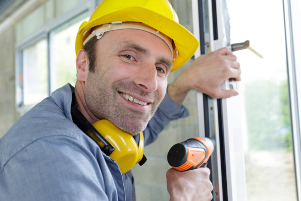 a man drilling window frame - Foto, afbeelding