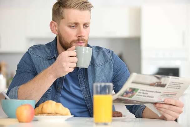 handsome young man with cup of coffee and newspaper - Foto, Imagem