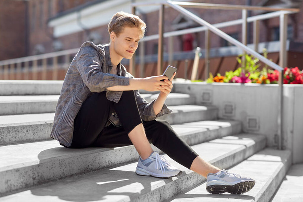 teenage boy using smartphone in city - Φωτογραφία, εικόνα