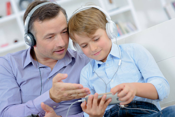 Dad and son wearing headphones - 写真・画像