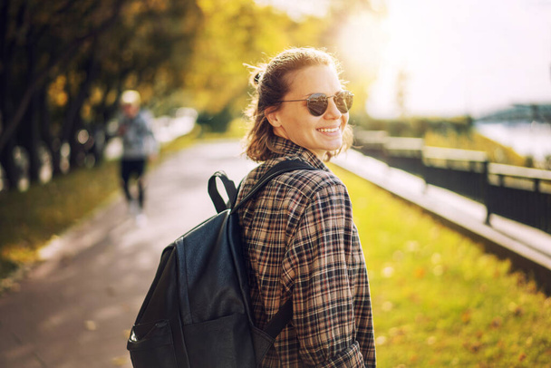 Hermosa joven mujer hipster rizado en gafas de sol caminando felizmente en la ciudad - Foto, imagen
