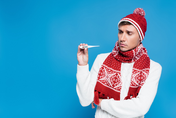 Sick and upset man in knitwear showing  thermometer isolated on blue - Photo, Image