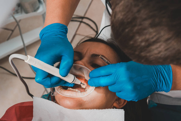 A fogorvosnál, fogkő eltávolítás, ultrahang, páciens és fogorvos. Visszahúzó az ajkak és íny elszigetelésére. 2020. - Fotó, kép