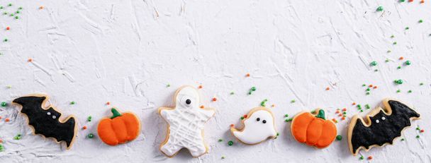 Top view of Halloween festive decorated icing gingerbread sugar cookies on white background with copy space and flat lay layout. - Foto, afbeelding