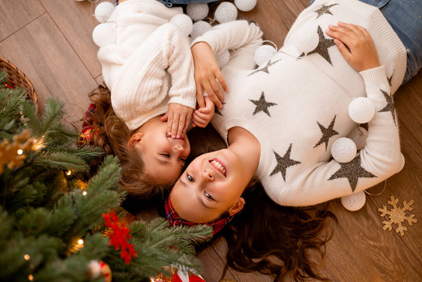 Two children sisters next to a Christmas tree view from above, space for text - Photo, Image
