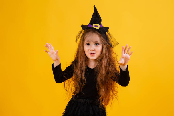 menina com longos sorrisos de cabelo vermelho em um traje de bruxa de Halloween. Halloween para crianças, espaço para texto - Foto, Imagem