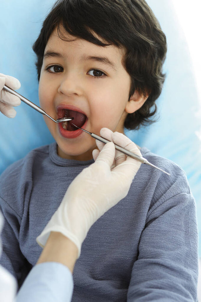 Little arab boy sitting at dental chair with open mouth during oral checking up with dentist doctor. Stomatology concept - Foto, Imagen