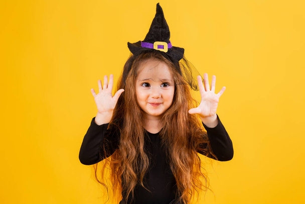 menina com longos sorrisos de cabelo vermelho em um traje de bruxa de Halloween. Halloween para crianças, espaço para texto - Foto, Imagem