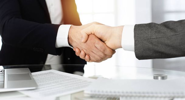Unknown diverse business people are shaking hands finishing contract signing in sunny office, close-up. Business handshake concept - Фото, зображення