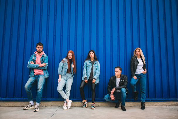 Группа из четырех молодых разнообразных друзей в джинсовой одежде выглядят беззаботно, молодые и счастливые на улицах города - Фото, изображение