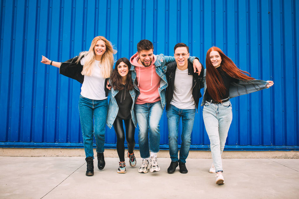 Group of four young diverse friends in jeanse outfit look carefree, young and happy on citys streets - Фото, изображение