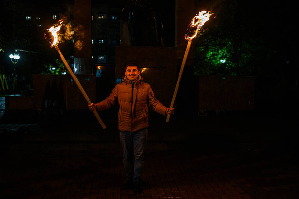 Мужчина держит два факела, мирного участника акции, вечер с факелами. 2020 - Фото, изображение