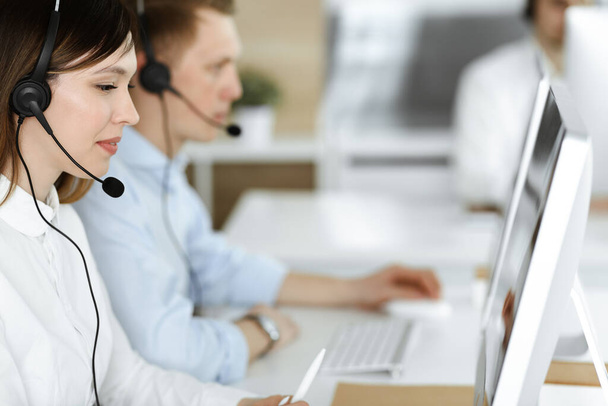 Group of diverse operators at work in call center. Beautiful asian woman sitting in headset at customer service office. Business concept - Фото, зображення