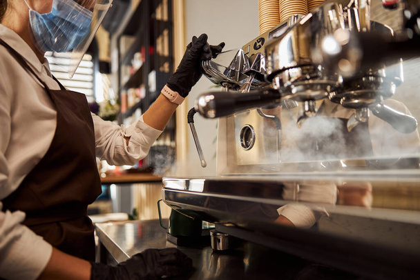 Woman waiter cleaning coffee machine in the cafe bar - Photo, Image