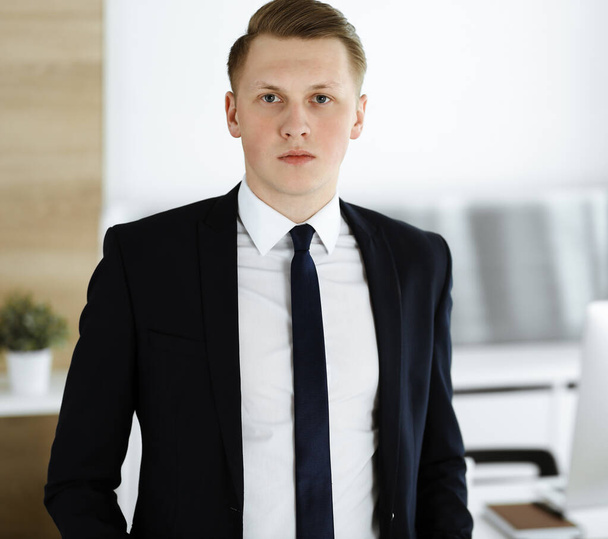 Cheerful businessman standing and looking at camera in office. Headshot of young and successful entrepreneur - Foto, afbeelding