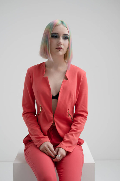 Portrait of a young beautiful informal blonde girl with dyed hair. Red jacket suit on the naked body. Studio photoshoot on a white background. - Foto, afbeelding