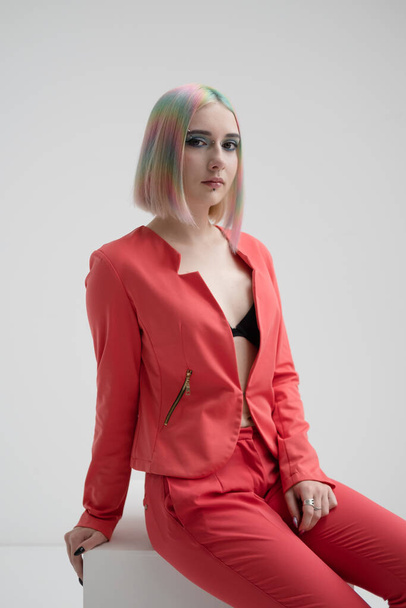 Portrait of a young beautiful informal blonde girl with dyed hair. Red jacket suit on the naked body. Studio photoshoot on a white background. - Photo, Image