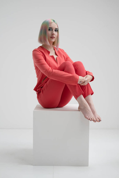 Portrait of a young beautiful informal blonde girl with dyed hair. Red jacket suit on the naked body. Studio photoshoot on a white background. - Photo, image