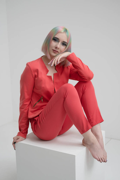Portrait of a young beautiful informal blonde girl with dyed hair. Red jacket suit on the naked body. Studio photoshoot on a white background. - Фото, изображение