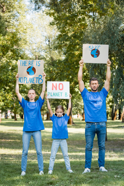 familia de activistas sosteniendo pancartas con el globo terráqueo, excepto, y sin inscripción planeta b en manos levantadas, concepto de ecología - Foto, imagen