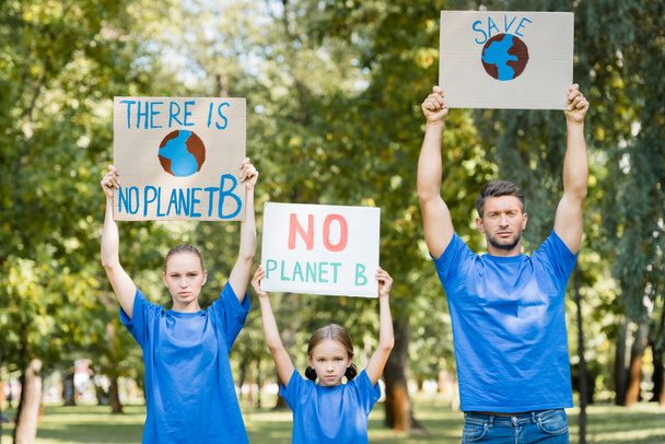family of volunteers holding placards with globe, save, and no planet b inscription in raised hands, ecology concept - Fotografie, Obrázek