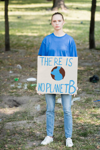 mujer mirando a la cámara mientras sostiene la pancarta con globo y no hay inscripción planeta b - Foto, imagen