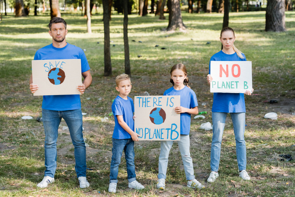два ребенка и родители держат плакаты с глобусом и нет планеты б надпись, экологическая концепция - Фото, изображение