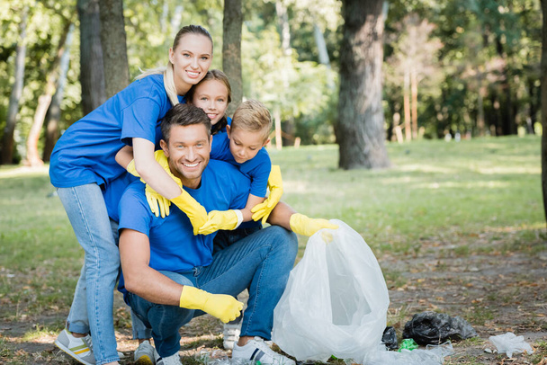 familia alegre abrazar padre sosteniendo bolsa reciclada en el bosque, concepto de ecología - Foto, Imagen