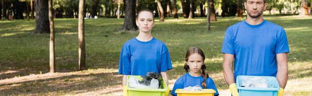 familia de voluntarios sosteniendo contenedores llenos de basura plástica, concepto de ecología, pancarta - Foto, imagen