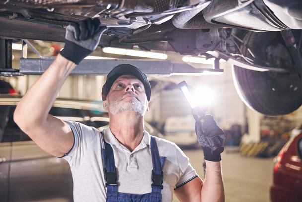 Szakállas férfi munkás javítás autó autószerelő műhelyben - Fotó, kép