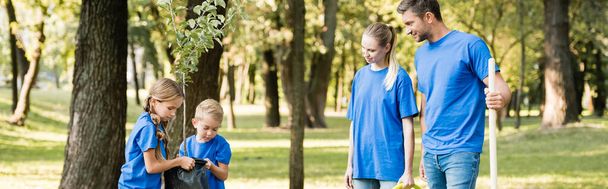 children carrying young tree near parents in forest, ecology concept, banner - Photo, Image
