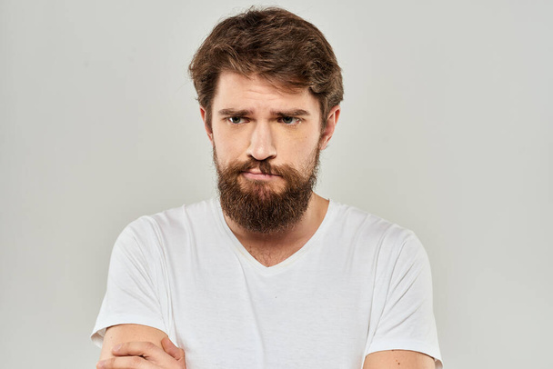 Uomo barbuto gesticolando con mano bianco ritagliato t-shirt stile di vita in studio - Foto, immagini
