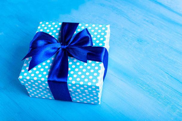 Blue gift box with a bow on a blue background. Holiday greeting card. - Fotó, kép