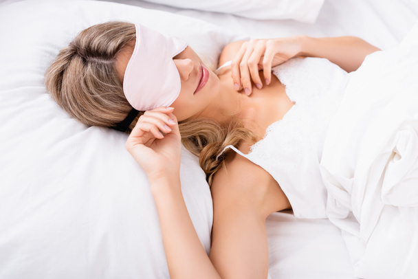 Young woman in blindfold lying on white bedding at morning  - Photo, Image
