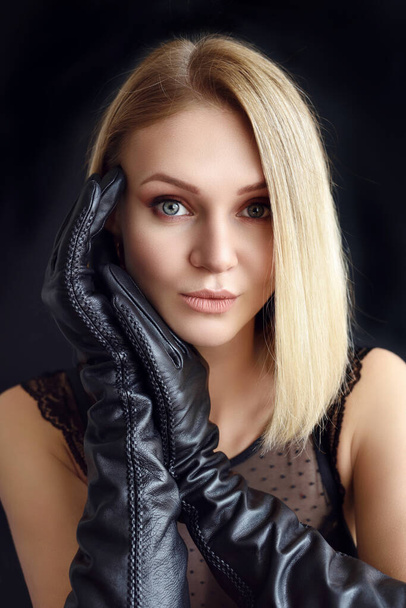 Beautiful sexy blonde in leather gloves on a black background - Zdjęcie, obraz