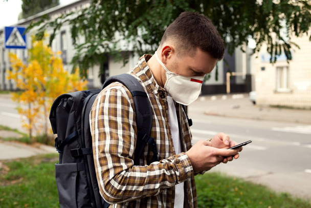 Young guy in a protective mask on the street. Coronavirus protection - Фото, изображение