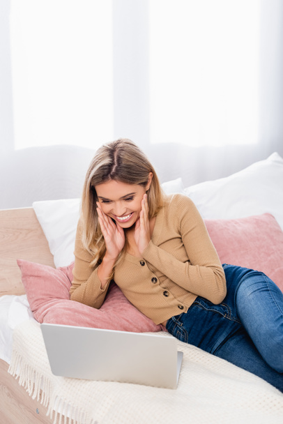 Cheerful teleworker using laptop in bedroom  - Fotó, kép