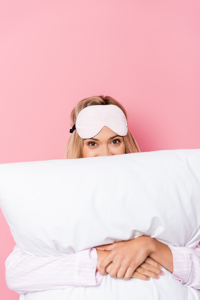 Young woman in blindfold covering face with pillow on pink background - 写真・画像