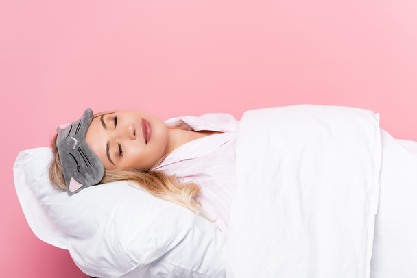 Jeune femme les yeux bandés dormant sur un oreiller avec couverture sur fond rose - Photo, image