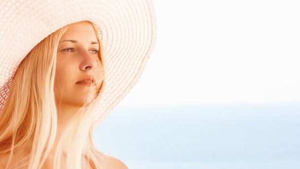 Femme aux cheveux blonds portant un chapeau, profitant du mode de vie en bord de mer et à la plage en été, des voyages de vacances et des loisirs - Photo, image