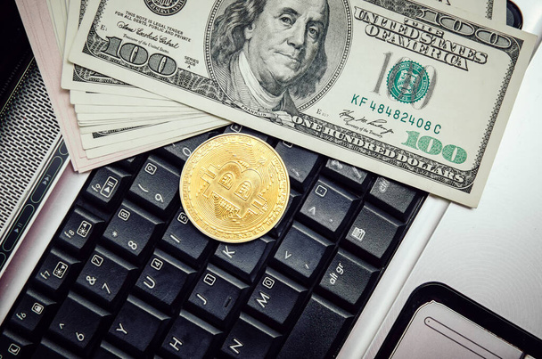 Bitcoin leży na klawiaturze laptopa z wiązką dolarów USA w zbliżeniu. Pojęcie przedsiębiorstwa i handlu. - Zdjęcie, obraz