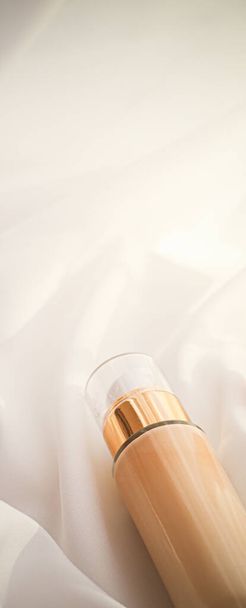 Tonal pansiyon krem şişesi makyaj sıvısı temeli ipek arka planda çıplak ten rengi lüks bir tatil tasarımı olarak kozmetik ürünü - Fotoğraf, Görsel