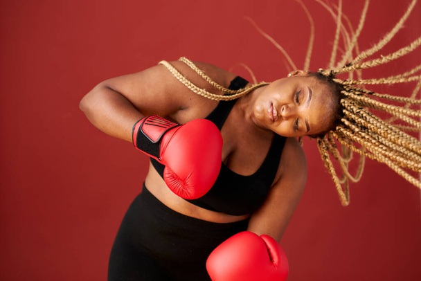 african oversize woman with red boxing mitts isolated on red background - Φωτογραφία, εικόνα