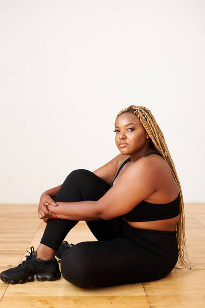 plump, plus size african american woman in sportswear posing in studio - Foto, afbeelding