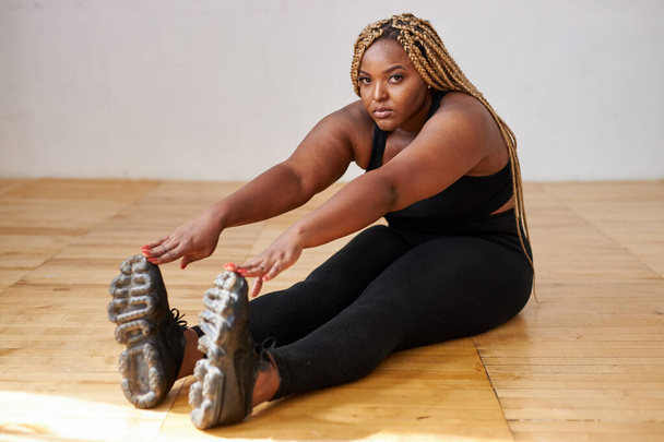 chubby african american woman do exercises sitting on the floor - Φωτογραφία, εικόνα