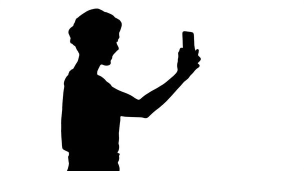 Silhouette Beautiful young woman walking and holding a smartphon - Foto, afbeelding