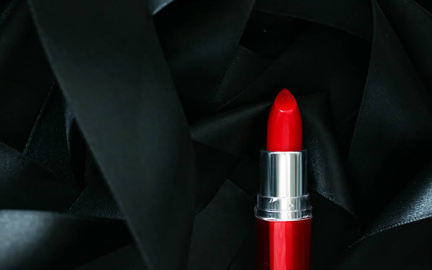 Rode lippenstift op zwarte zijde achtergrond, luxe make-up en schoonheid cosmetische - Foto, afbeelding