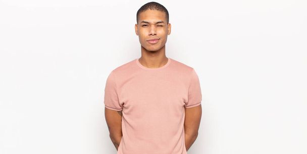 young black man looking happy and friendly, smiling and winking an eye at you with a positive attitude - Фото, изображение