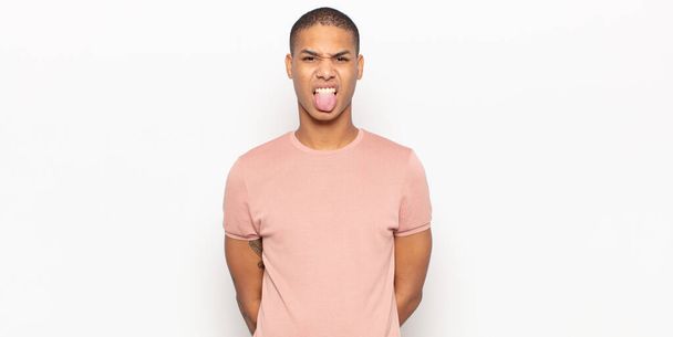 young black man feeling disgusted and irritated, sticking tongue out, disliking something nasty and yucky - 写真・画像