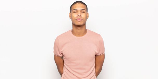 young black man pressing lips together with a cute, fun, happy, lovely expression, sending a kiss - Foto, afbeelding